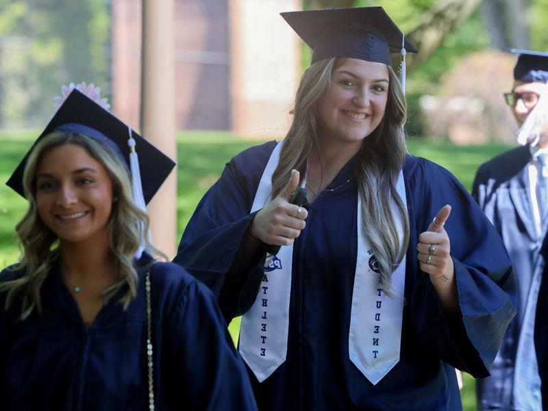 两个女人戴着毕业典礼的帽子，穿着毕业礼服走在外面.