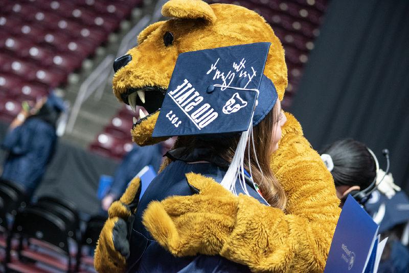 尼塔尼狮子拥抱一名戴着帽子的毕业生，帽子上写着“为了旧州的荣耀2023”。